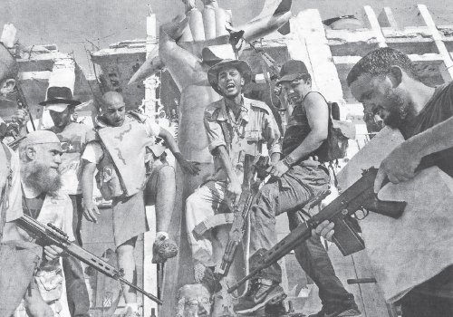 Un grupo de rebeldes festeja y apunta sus armas contra la cabeza de una estatua de Kadafi derribada dentro del complejo del lder libio, en Trpoli